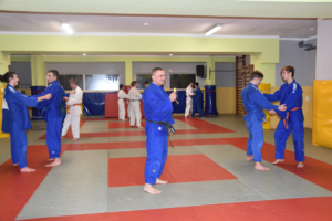 Trening zawodników trenujących judo. Na środku trener Grzegorz Maj trzymający w ręku żółty gwizdekpng