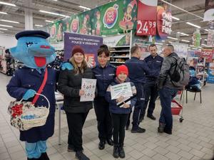 policjantka wraz z klientkami i maskotką Polisią na pamiątkowej fotografii podczas akcji profilaktycznej Bezpieczne Zakupy w Auchan