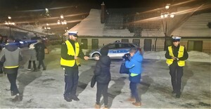 policjanci ruchu drogowego wręczają odblaski na parkingu kościelnym