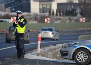 Policjant ruchu drogowego stoi przy krawędzi jezdni - dokonuje pomiaru prędkości