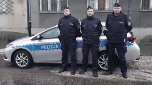 Trzech dzielnicowych w mundurach stoi przed radiowozem