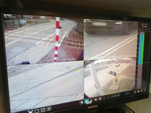 Ekran monitora podzielony na cztery mniejsze ekrany obejmujacy zasiegiem przejazd kolejowy. W prawym górnym widoczny samochód osobowy