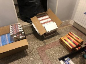 dwa kartony wypełnione nielegalnymi paczkami papierosów i lezących luzem obok kilka wagonów papierosów