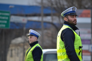 Dwóch policjantów ruchu drogowego nadzoruje ruch. Oboje stoją w penej od...