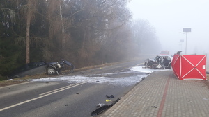 Dwa pojazdy ze zniszczonymi i porozrzucanymi elementami przodów pojazdów stoją na drodze