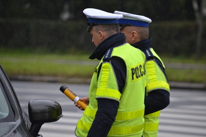 Dwóch policjantów ruchu drogowego podczas kontroli drogowej bada trzeźwość