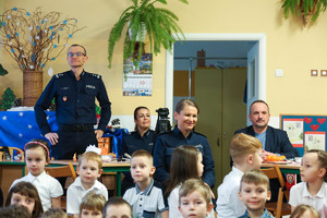 Policjanci oglądają występ grupy teatralnej stojąc za dziećmi