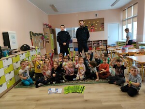 policjanci i dzieci pozują w sali do wspólnego zdjęcia