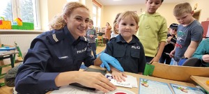 policjantka wykonuje odciski linii papilarnych dziewczynce w mundurku policyjnym