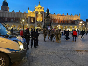 policjanci na płycie Rynku Głównego w trakcie zabezpieczenia w tle Sukiennice, na pierwszym planie fragment radiowozu