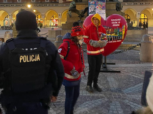 policjant patroluje Rynek Głowny a obo dzieci zbierja na WOŚP