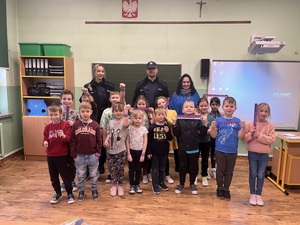 Prelekcje dla dzieci przed feriami 2023 Przeciszów  wspólne zdjęcie dzieci z policjantem prezentacja opasek odblaskowych