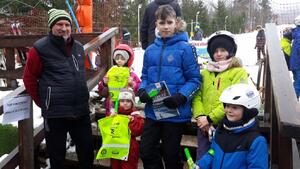 Dzieci z opiekunem stoją na tle wyciągu narciarskiego z upominkami otrzymanymi od Policjantów