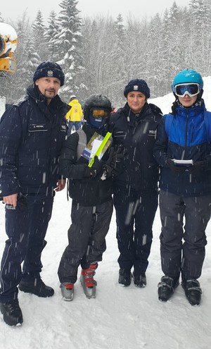 Od lewej umundurowany policjant, obok niego chłopak w stroju narciarskim, następni umundurowana policjantka i obok niej również chłopak w stroju narciarskim.