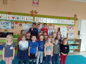 dzieci w sali przedszkola pozują do wspólnego zdjęcia z policjantką