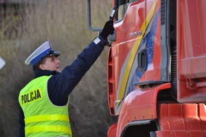 Policjant ruchu drogowego bada kierującego samochodem ciężarowym urządzeniem elektronicznym na zawartość alkoholu w wydychanym powietrzu