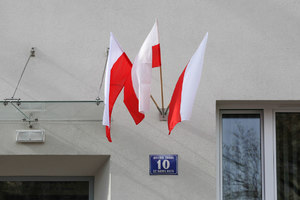 Trzy polskie flagi na wejściem do budynku