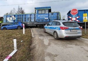 Na zdjęciu obok niebieskiej lokomotywy widać ustawionego równolegle volkswagena  w kolorze niebieskim, który został zepchnięty przez pociąg z torów. Na zdjęciu widać również oznakowany radiowóz.