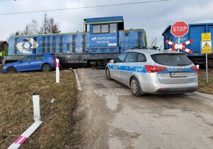 Na zdjęciu obok niebieskiej lokomotywy widać ustawionego równolegle volkswagena  w kolorze niebieskim, który został zepchnięty przez pociąg z torów. Na zdjęciu widać również oznakowany radiowóz.