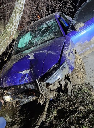 Rozbity, niebieski samochód marki Audi, kóy uderzył w dzewo