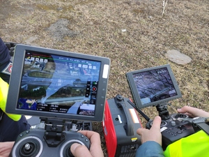 Dwa kontrolery podglądu kamery drona osługiwane  przez człowieka