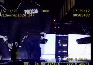 zdjęcie z policyjnego wideorejestratora przedstawiające dwóch umundurowanych policjantów podczas kontroli osobowego mitshubishi