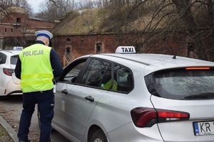 policjant ruchu drogowego stojący przy kontrolowanej taksówce