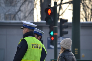 Dwóch policjantów ruchu drogowego nadzoruje ruch na drodze przy przejściu dla pieszych