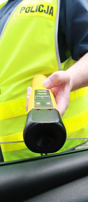 Policjant trzymający w ręce urządzenie do badania stanu trzeźwości