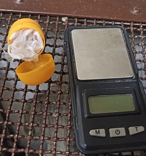 KPP Oświęcim. Zabezpieczony pojemnik z woreczkiem amfetaminy obok waga elektroniczna