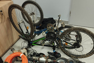 odzyskane rowery, sprzęt budowlany i elektryczny oraz zielony plecak. Rzeczy ułozone na podłodze
