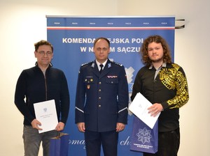 wspólne zdjęcie komendanta i wyróżnionych mężczyzn na tle banneru sądeckiej Policji