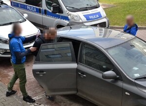 drugi z zatrzymanych wsiada do nieoznakowanego radiowozu, obok nieumundurowani policjanci