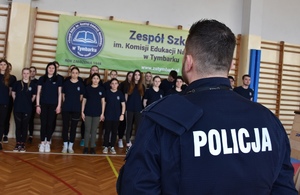 policjant rozmawia z uczniami którzy stoją w dwuszeregu
