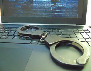 Oszustwo internetowe laptop  na klawiaturze kajdanki