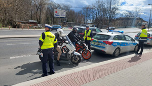 policjanci w trakcie kontroli kirujących motocyklami stojący za radiowozem na jednej z krakowskich ulic