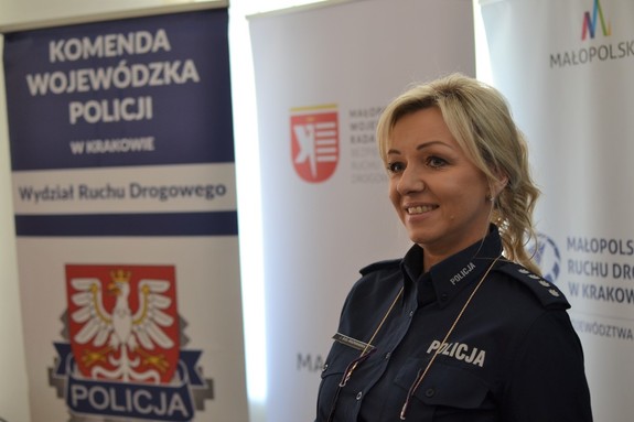 Policjantka porwadzi prelekcję. W tle roll-up WRD KWP w Krakowie