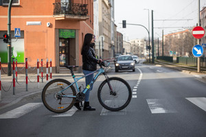 kobieta przeprowadza rower przez pasy