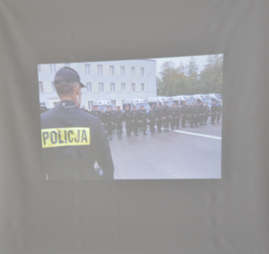 Wyświetlony fragment prezentacji multimedialnej prezentujący policjantów oraz policyjne radiowozy