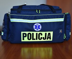 Na zdjęciu widoczna jest apteczka koloru niebieskiego z żółtymi, odblaskowymi pasami i  napisem „Policja”. Apteczka jest zamknięta.