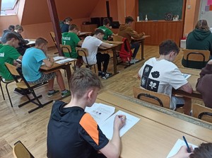Uczniowie siedzący w klasie, którzy rozwiązują test.