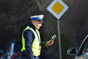 Policjant ruchu drogowego przeprowadza szybkie badanie trzeźwości urządzeniem elektronicznym