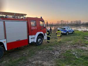 wóz państwowej strazy pożarnej, radiowóz, strażacy i policjantka. w tle rzeka Wisła