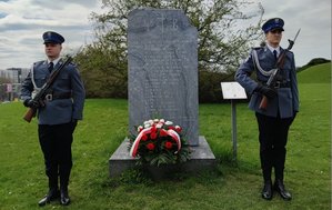 Tablica pamiątkowa pomordowanym policjantów na Płaszowie obok kwiaty i policjanci komapnii honorowej