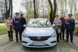 Podarowany samochód z lewej i prawej strony członkowie stowarzyszenia oraz komendant Leśniak