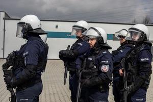 Policjanci Nieetatowych Pododdziałów Prewencji uzbrojeni w strzelby gładkolufowe stojący w szyku