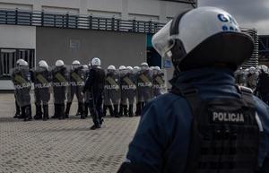 Dowódca NPP stojący tyłem do fotografa, na drugim planie widać formujące się szyki policyjne