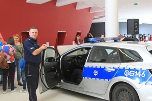 Policjant stoi przy policyjnym radiowozie