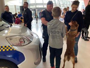 Policyjny przewodnik psa słuzbowego rozmawia z kobietą i dzieckiem, którzy głaszczą policyjnego czworonoga