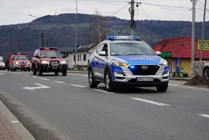jadący policyjny dariowóz prowadzący kolumne pojazdow strazy bioracych udział w ćwiczeniach